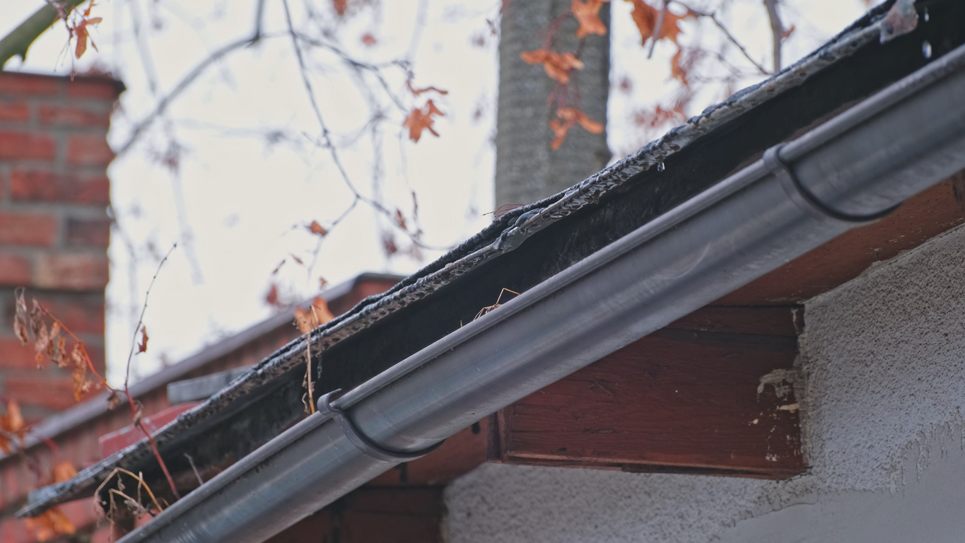 Rainwater Dripping from Roof Edge Into Plastic Gutter